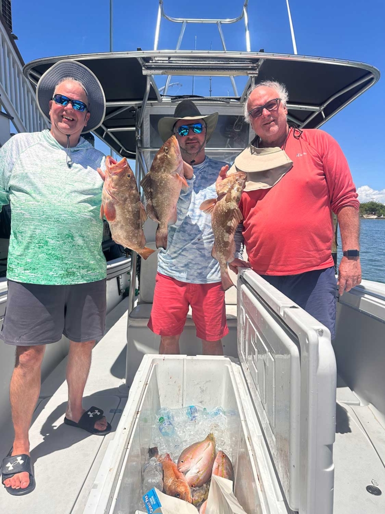 Three anglers holding some grouper